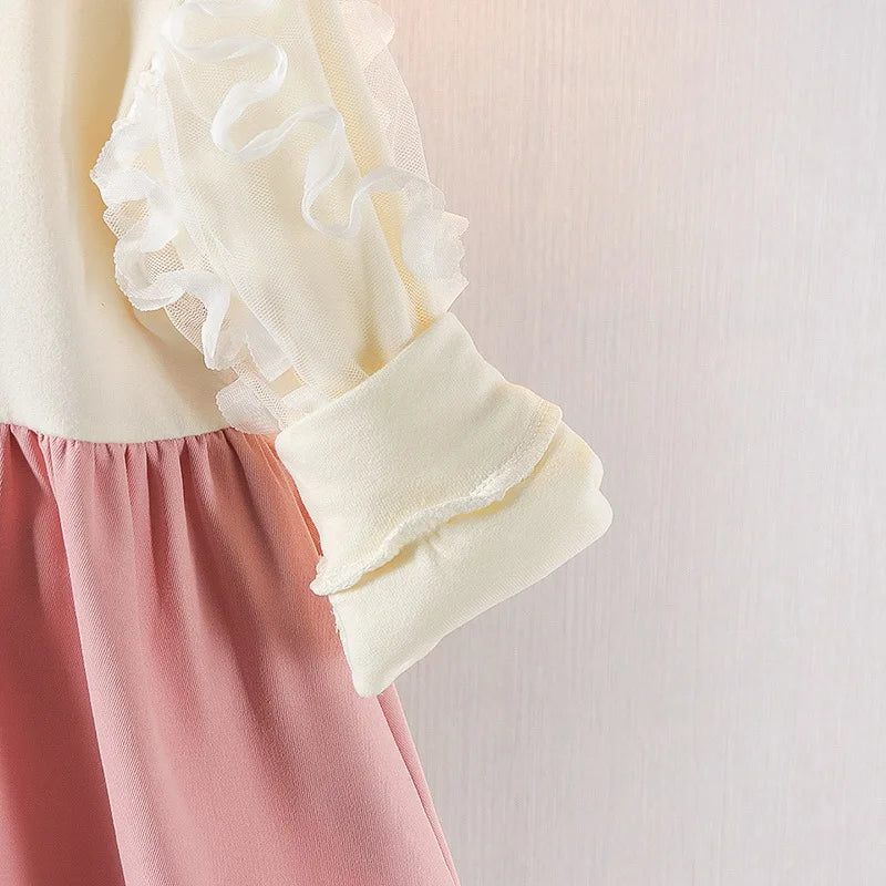 Close-up of a cream-colored top with ruffled sleeves and pink pants on a light background