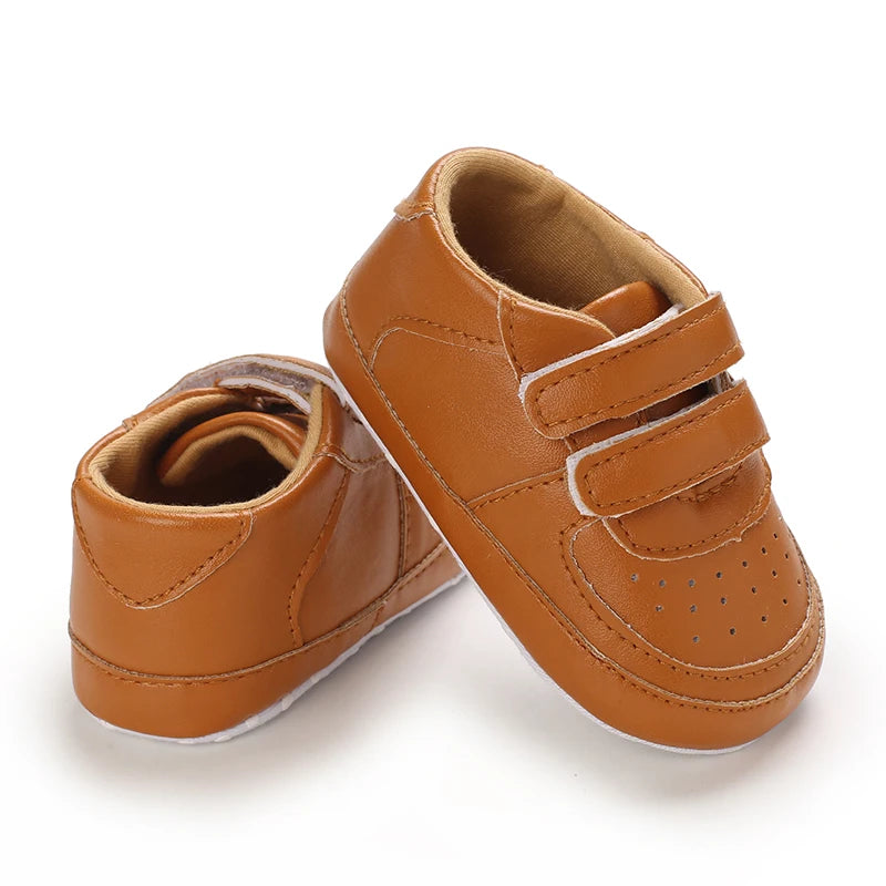 Pair of brown baby shoes with velcro straps on a white background