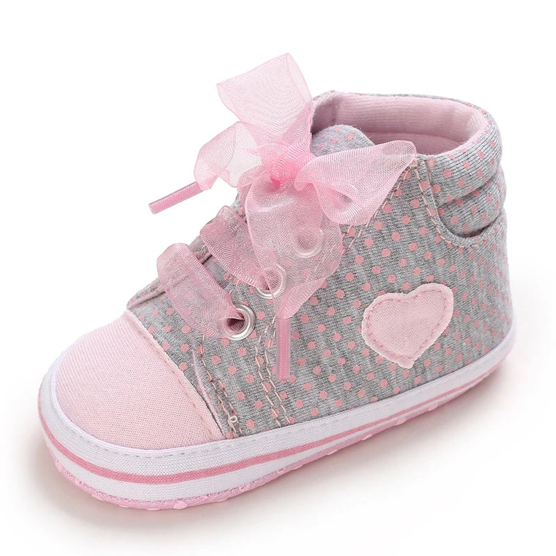 Pink and gray baby shoe with heart design and bow on a white background