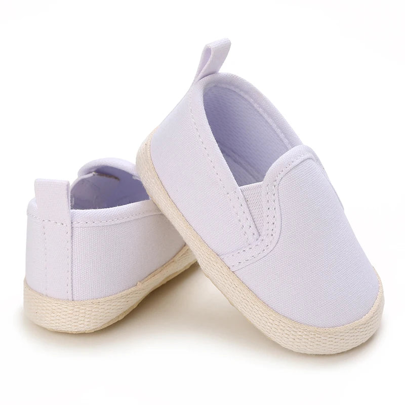 Pair of white baby shoes with light purple soles on a white background
