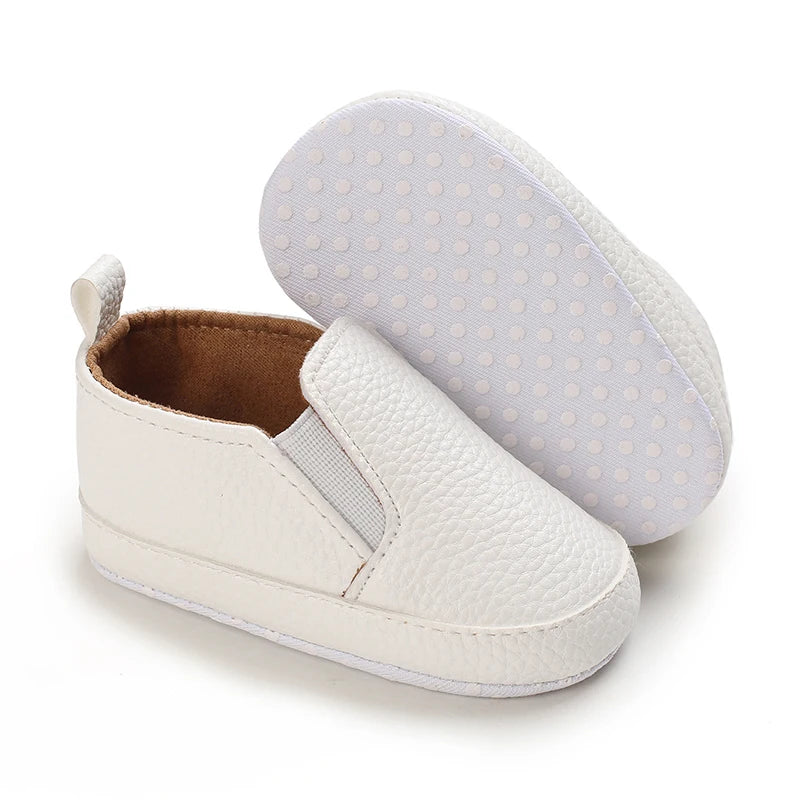 White baby shoes with brown sole on a white background