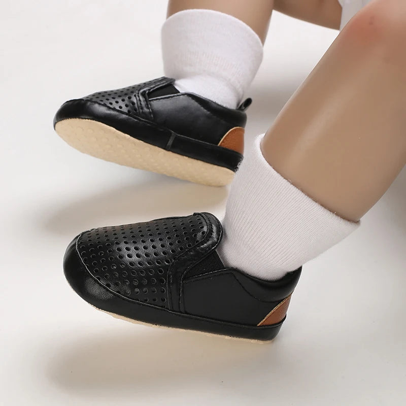 Black shoes with brown accents worn by a person on a white background