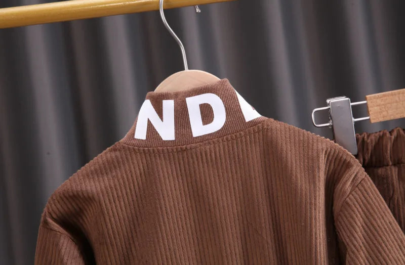 Brown jacket with 'ND' logo on a hanger against a dark curtain background