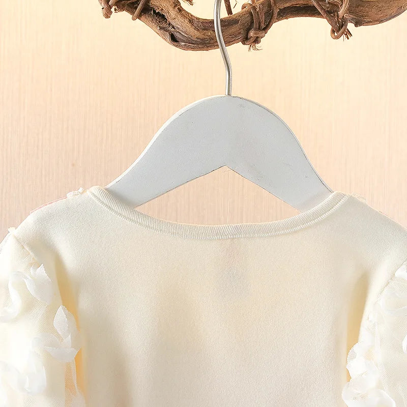 White baby dress on a gray hanger against a beige background