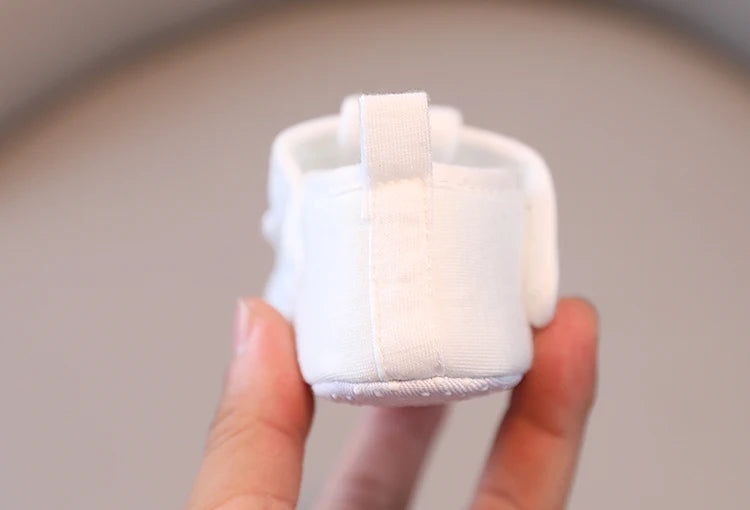 Small white ceramic mug held in a hand against a neutral background