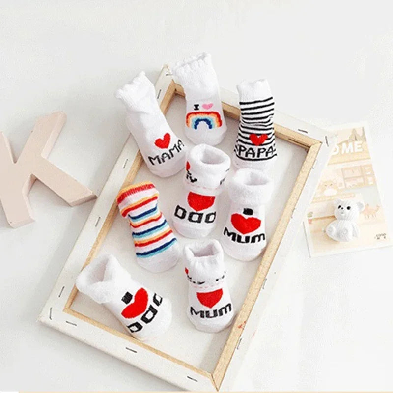 Set of baby socks with text and designs on a wooden tray