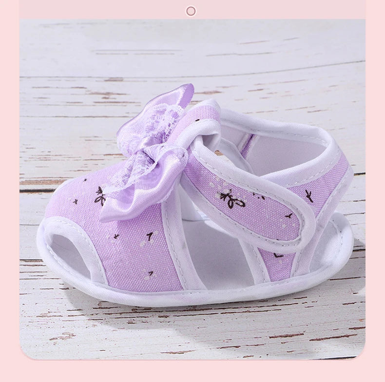 Purple baby shoes with a bow on a light wooden surface