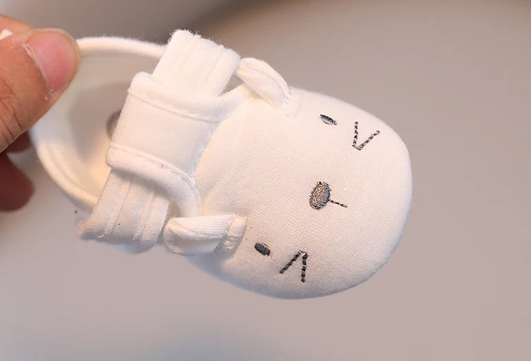 White plush keychain with a face design on a light gray background