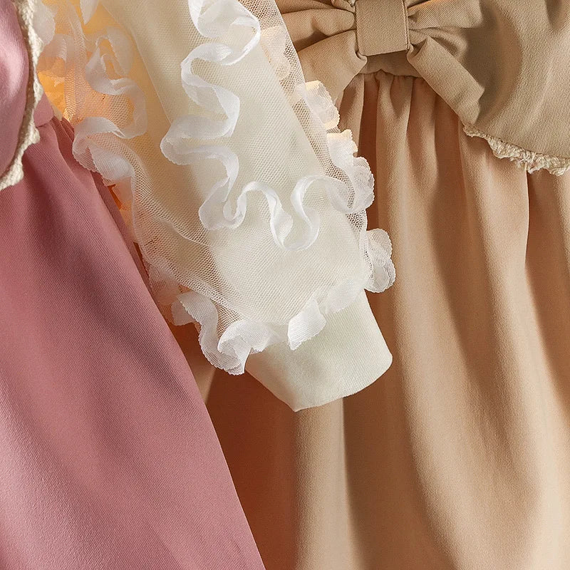 Close-up of a baby outfit with ruffled details in pink, beige, and white.