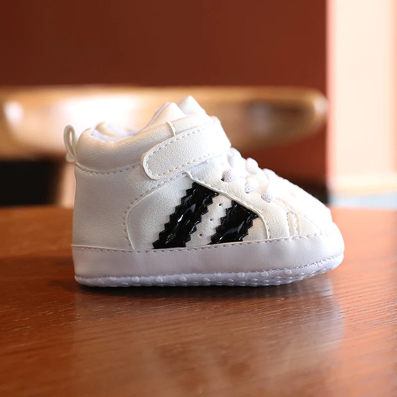 White baby shoe with black stripes on a wooden surface