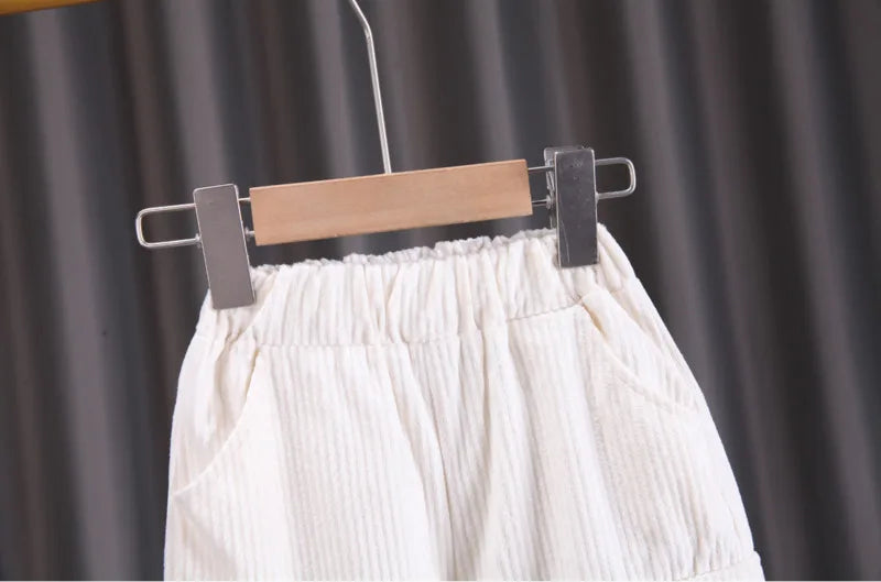White pleated skirt on a hanger against a dark curtain background
