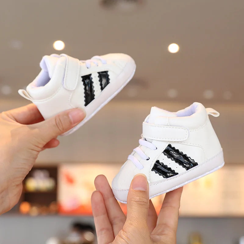 White sneakers with black stripes held by a person against a blurred indoor background