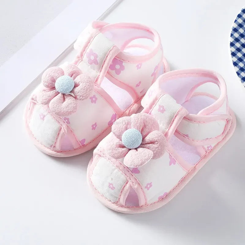Pair of pink baby sandals with floral designs on a white background