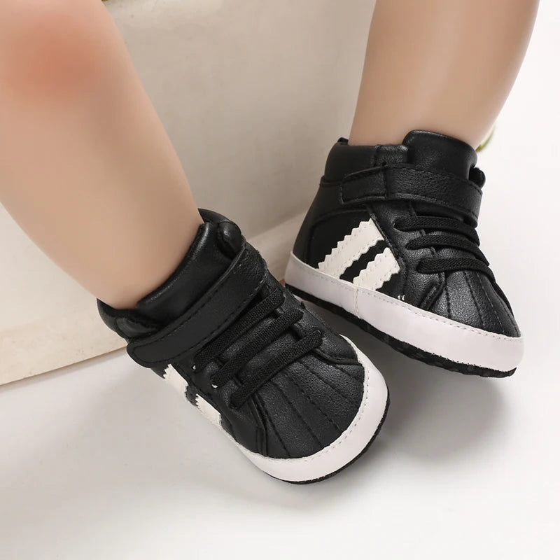 Black high-top sneakers with white soles worn by a child on a neutral background