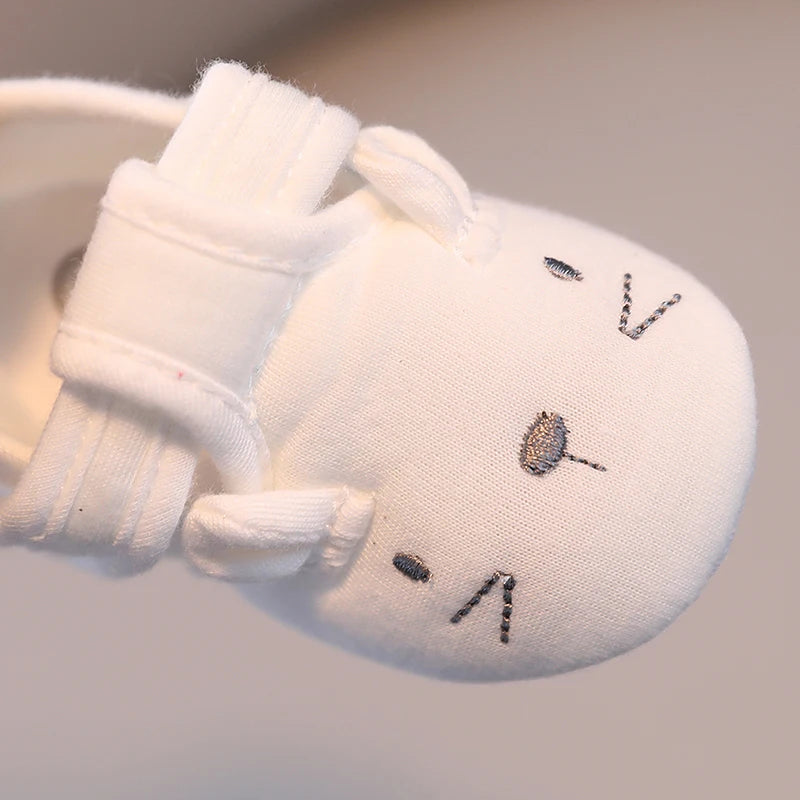 White plush toy with embroidered face on a light gray background