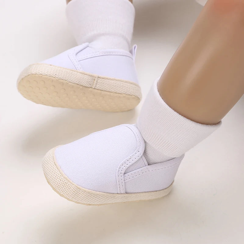 White baby shoes with beige soles on a light background
