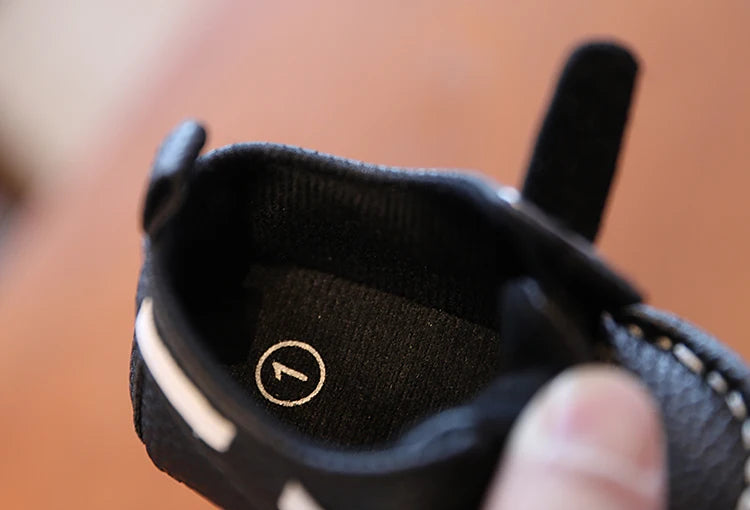 Close-up of a black shoe with a brand logo on a blurred background