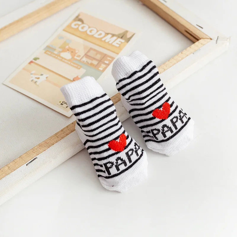 Pair of baby socks with 'Papa' and heart designs on a light surface.