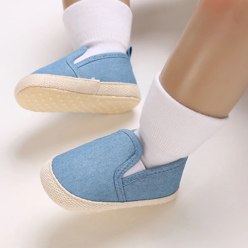 Blue baby shoes worn with white socks on a light background