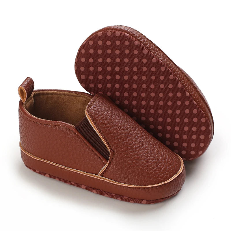Brown baby shoes with textured soles on a white background