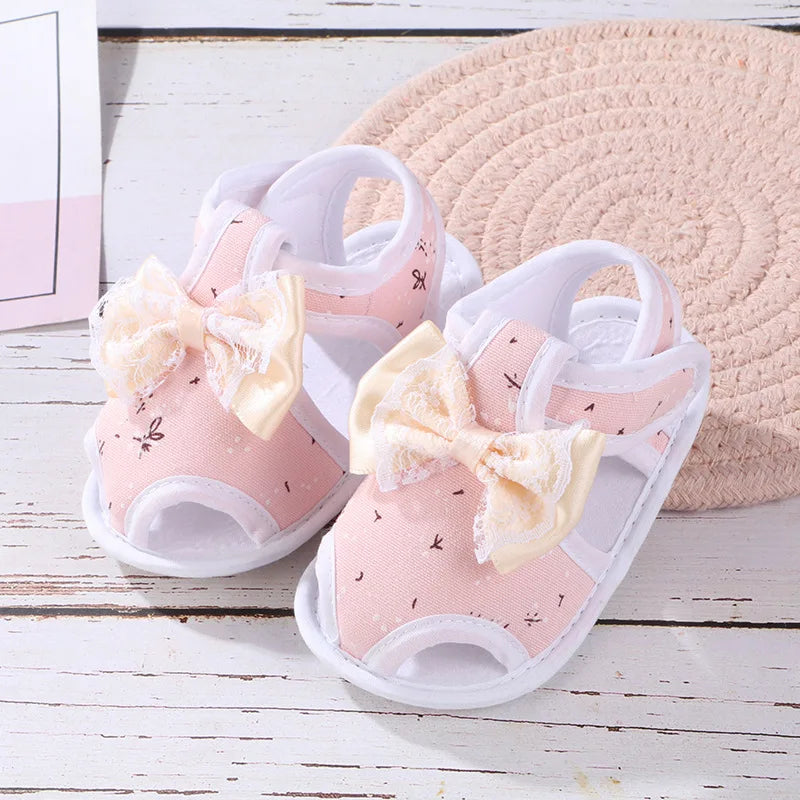 Pink sandals with bow decorations on a wooden surface