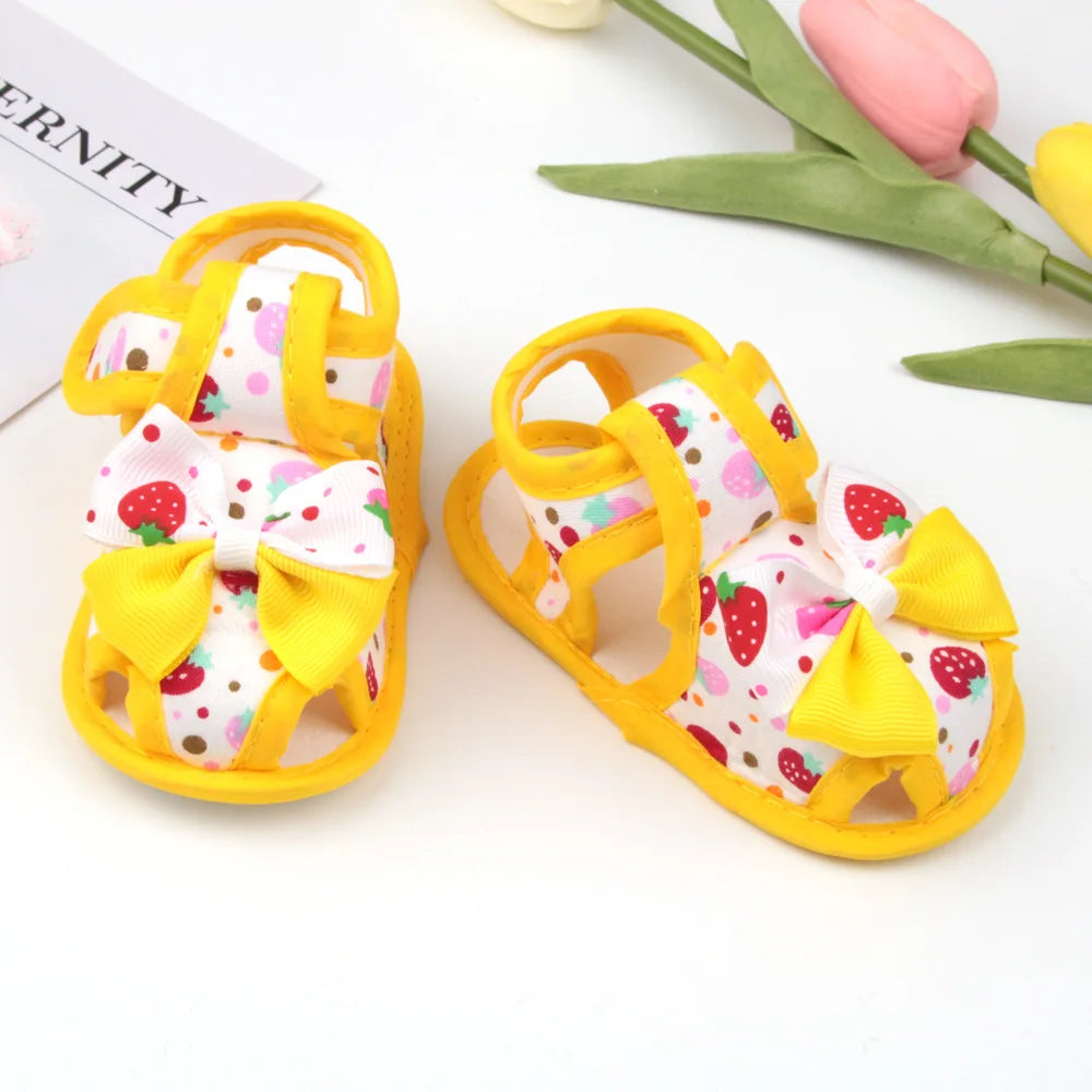 Pair of yellow children's sandals with strawberry pattern on a white background