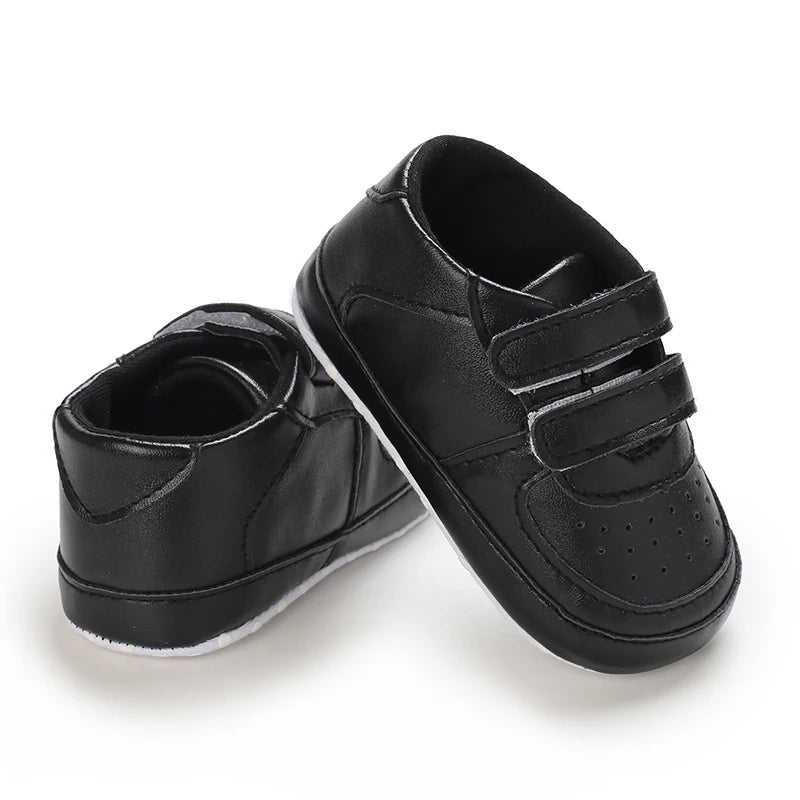 Pair of black children's shoes with velcro straps on a white background