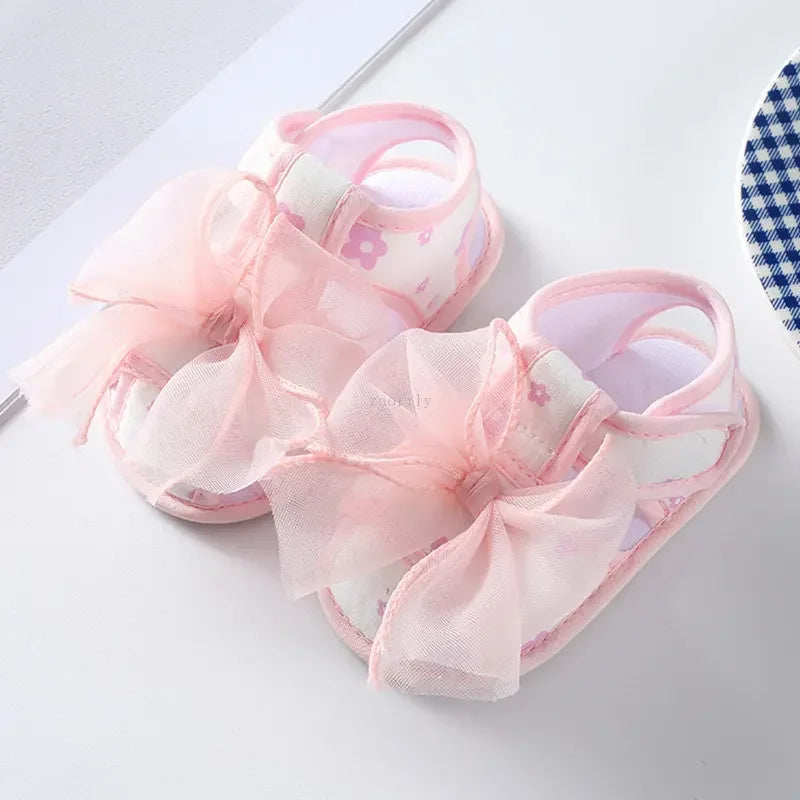 Pink baby sandals with floral patterns on a white background