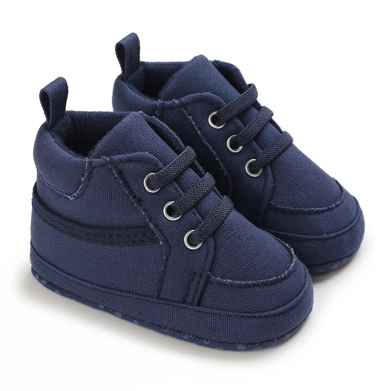 Pair of navy blue baby shoes with lace-up design on a white background