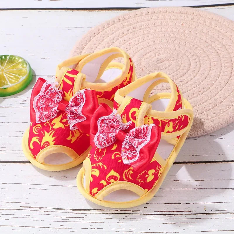 Red and yellow children's sandals with butterfly design on a wooden surface.