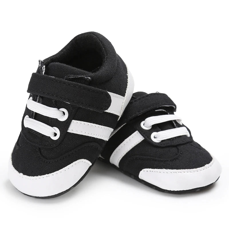 Black and white baby sneakers with velcro straps on a white background
