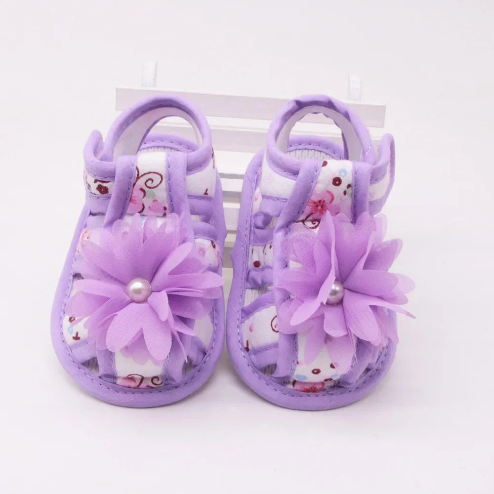 Pair of purple baby sandals with floral designs on a white background