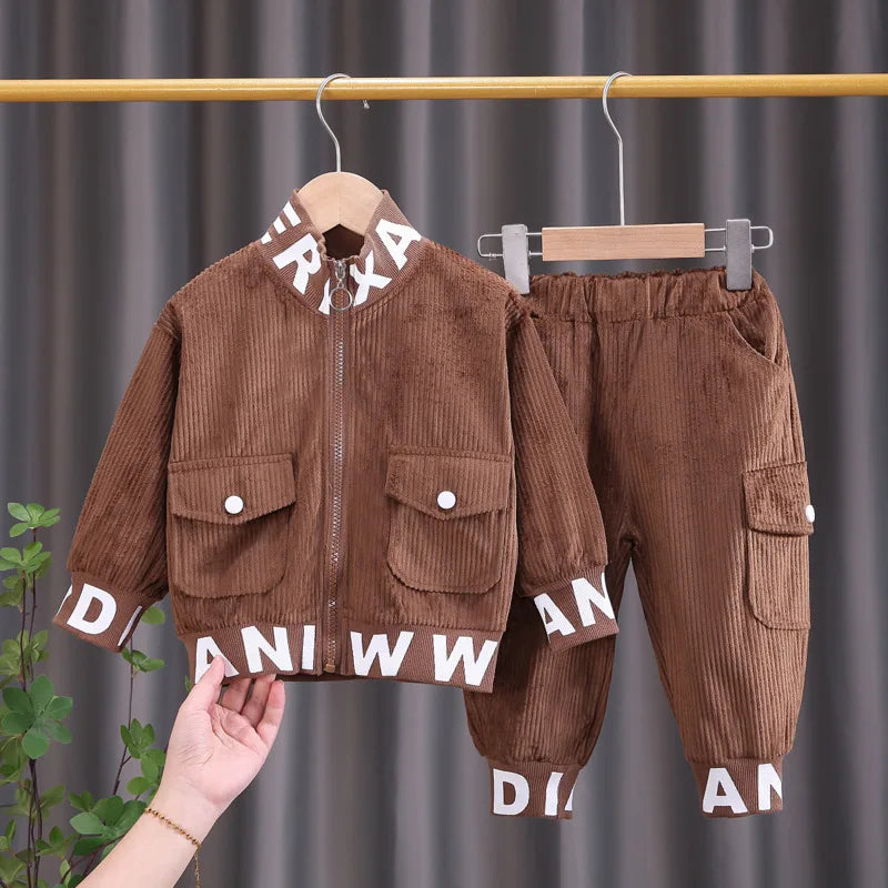 Brown corduroy outfit with lettering on a hanger against a gray curtain background