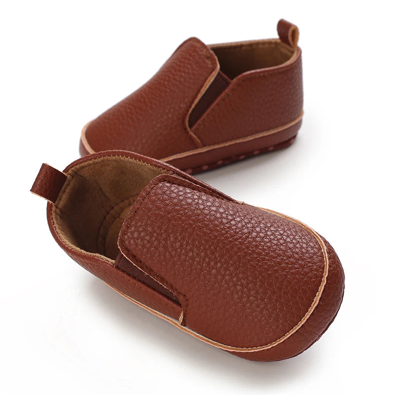 Pair of brown leather baby shoes on a white background