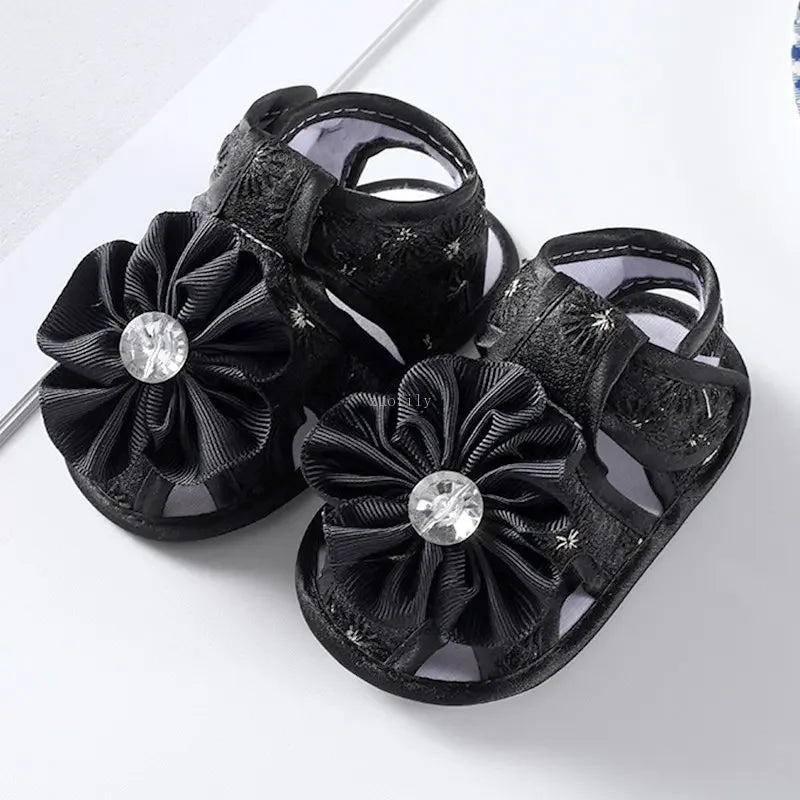 Black sandals with floral designs and rhinestones on a white background