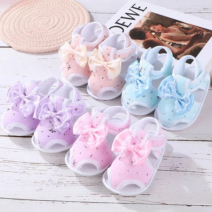 Colorful baby shoes with bows on a wooden surface