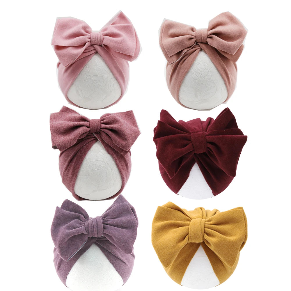 Set of six baby headbands with large bows in various colors on a white background