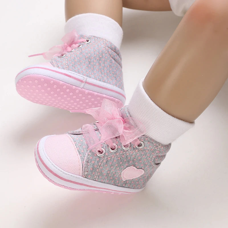 Children's shoes with pink ribbons and heart designs on a light background