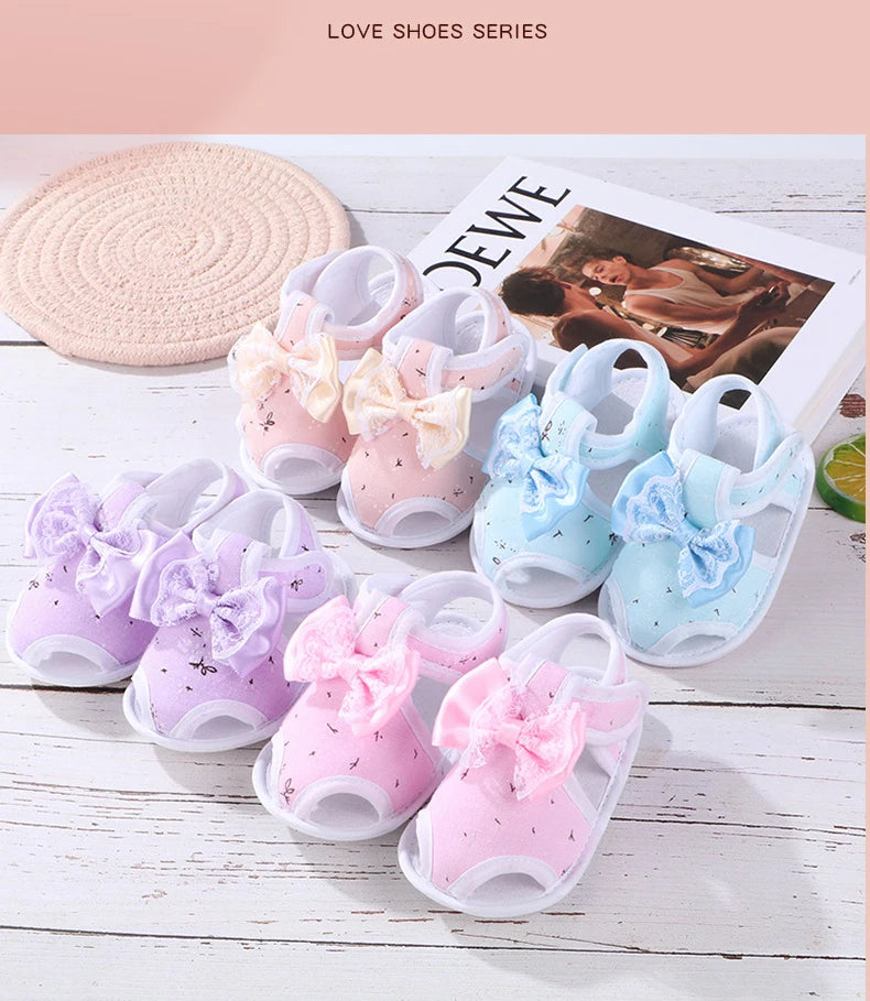 Set of baby shoes with bows in pink, blue, and purple on a wooden surface.