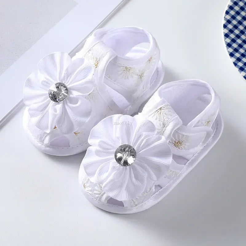White slippers with floral designs and rhinestones on a white background