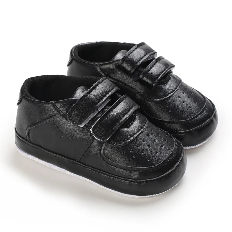 Pair of black baby shoes with velcro straps on a white background